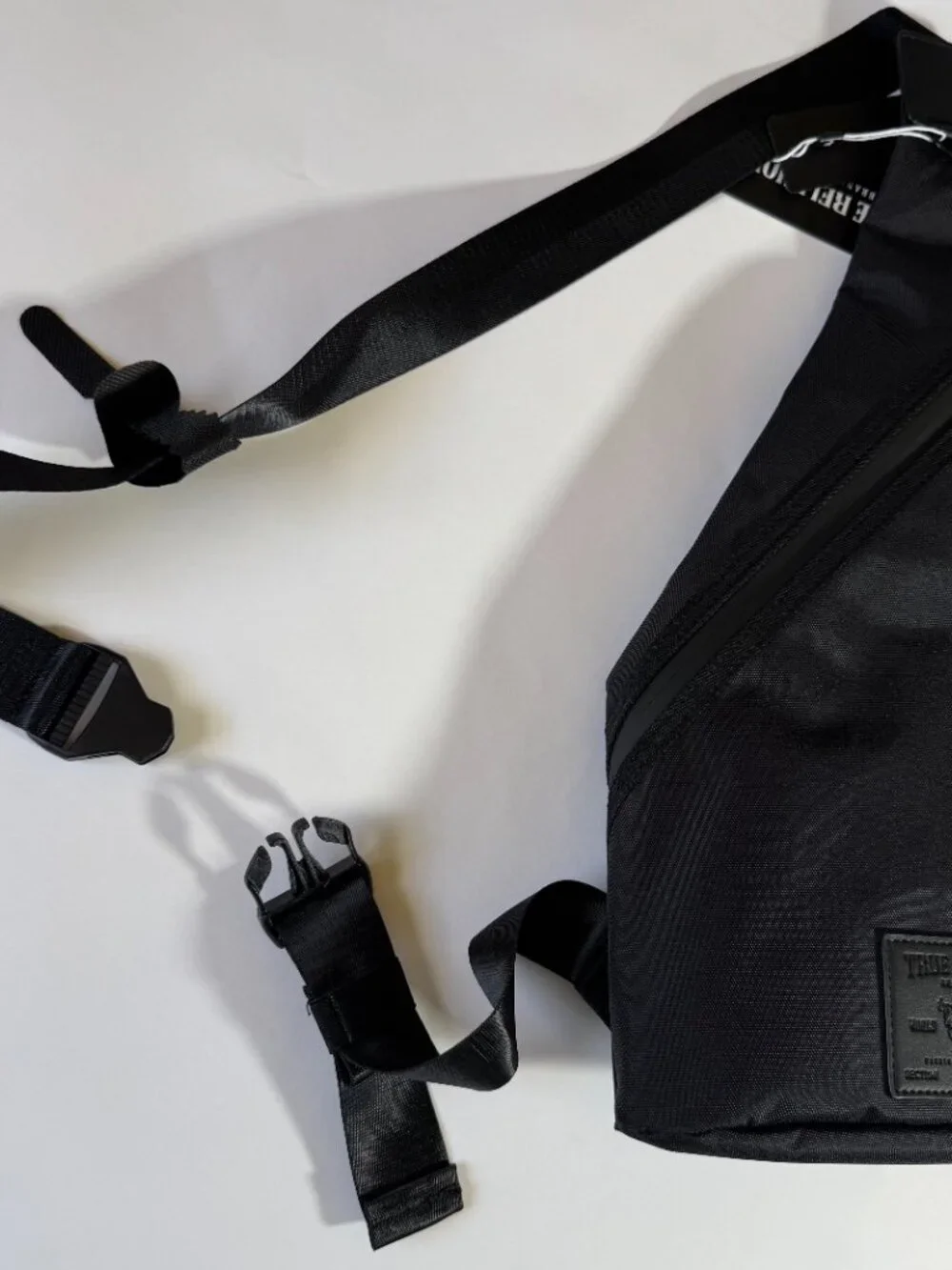 True Religion Black Sling Bag Features a Textured Black Logo Patch on the Front